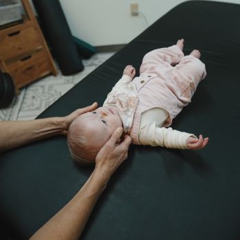 Provider using gentle manual therapy on baby head and neck for scoliosis support in Lakewood, Colorado